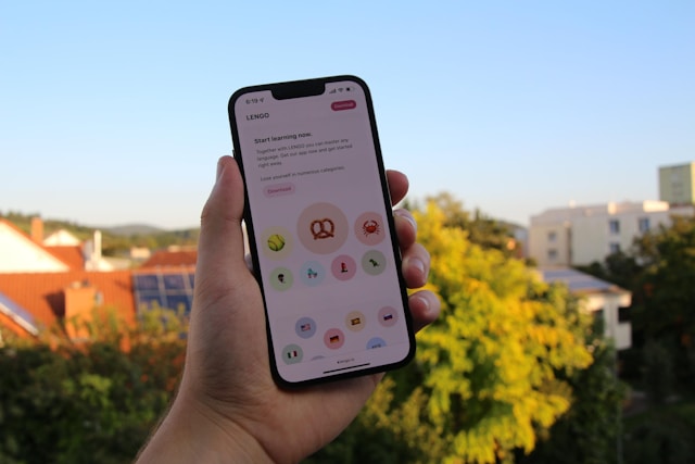 شخص يحمل هاتفاً مع تطبيق لغة مفتوح على شاشته.

