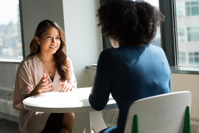 Duas mulheres de negócios discutem o uso de um serviço de tradução juramentada. 