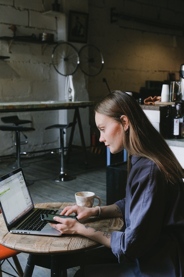 Uma jovem empresária usando um laptop em um café para traduzir documentos.