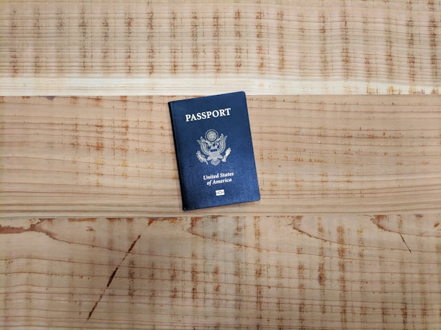 Um passaporte americano azul em uma mesa de madeira. 
