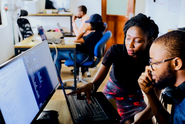 Duas pessoas trabalhando juntas em um sistema de computador em um escritório. 
