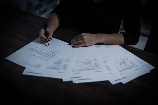 Uma pessoa examina uma pilha de documentos em uma mesa.