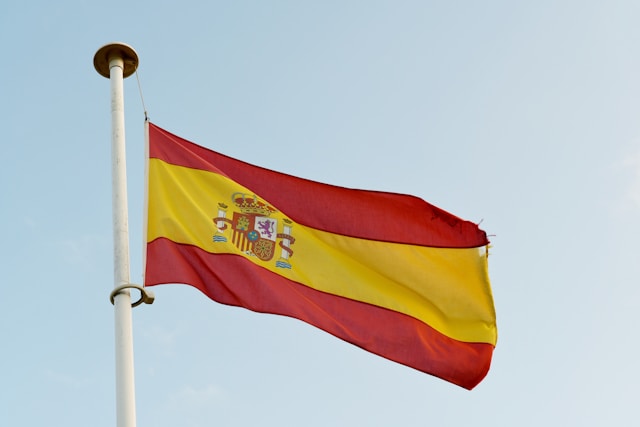 Uma imagem em close da bandeira da Espanha tremulando no alto do céu a partir de um mastro