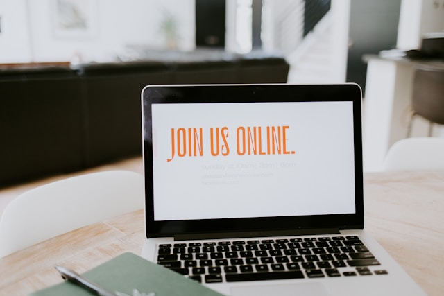 Um MacBook em uma mesa com a tela exibindo "Join us online".
