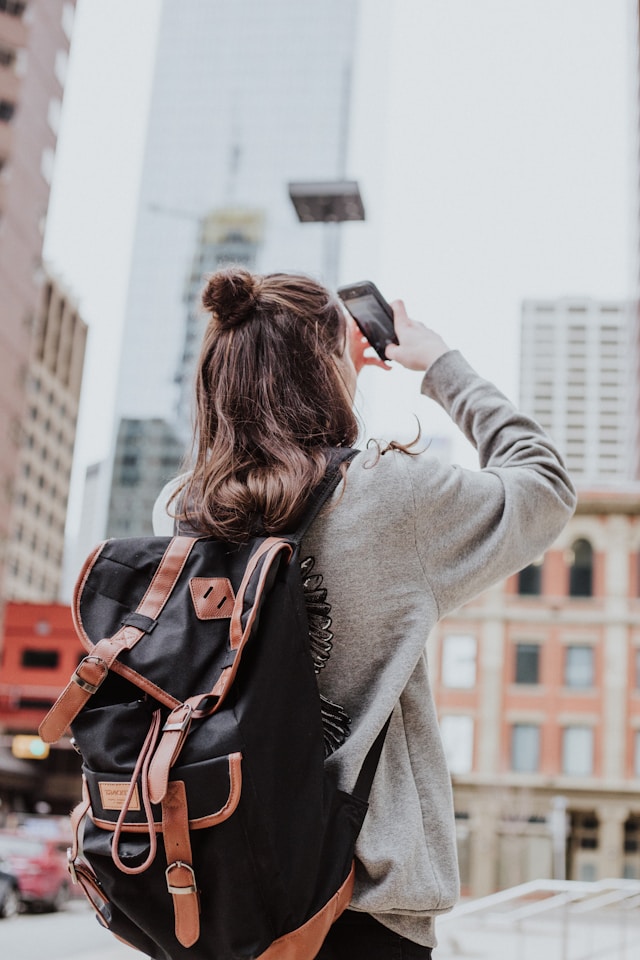 Uma pessoa usando uma mochila usa o celular para tirar uma foto de um outdoor.