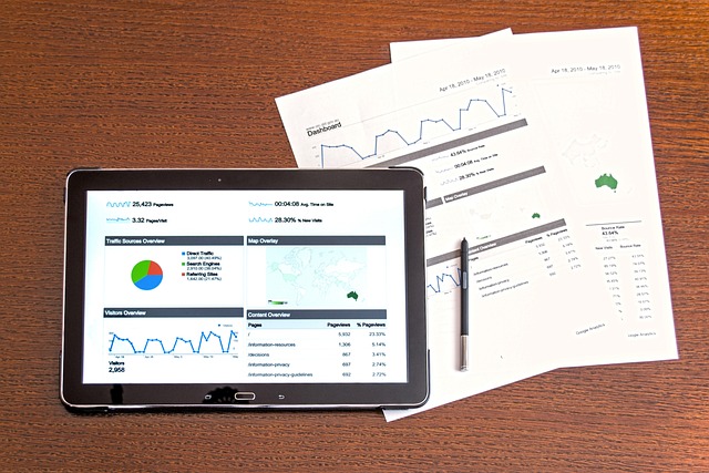 Os relatórios e gráficos de análise estão em um tablet digital e o papel em uma superfície de madeira.
