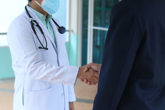 Um médico está em um aperto de mão com uma pessoa vestindo um terno azul.
