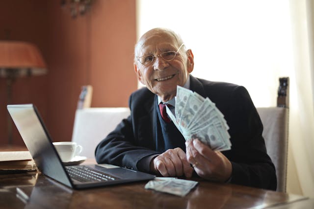 Alguém em uma mesa de trabalho segura notas de dólar.
