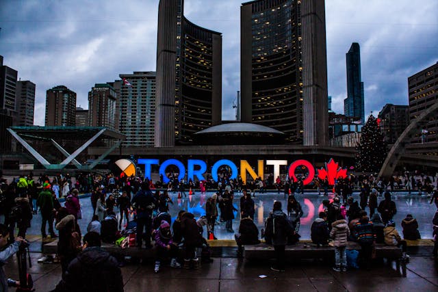 Um grupo de pessoas está diante de uma placa de sinalização de Toronto.