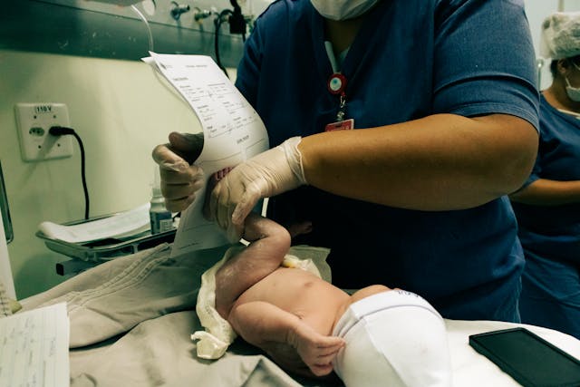 Um médico carimba uma certidão de nascimento com o pé de uma criança.
