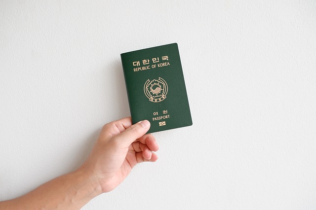 Uma mão segura um passaporte de viagem coreano em um fundo branco.
