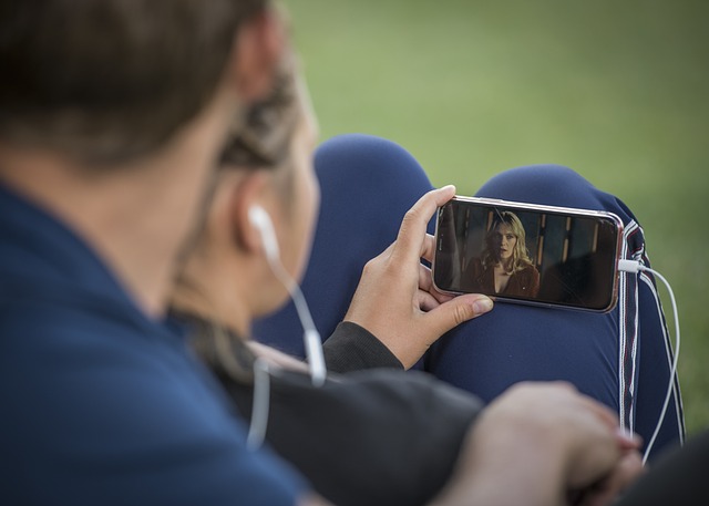 Visão traseira de duas pessoas assistindo a um vídeo em um smartphone.
