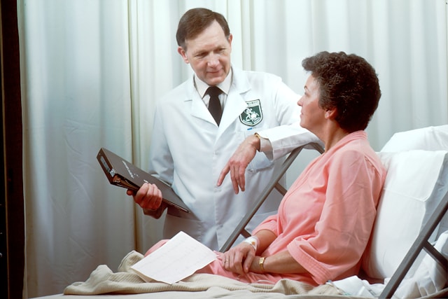 Um médico conversando com um paciente em uma cama de hospital.