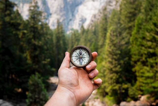 Ein Foto von jemandem, der in einem bewaldeten Gebiet einen Kompass hält.