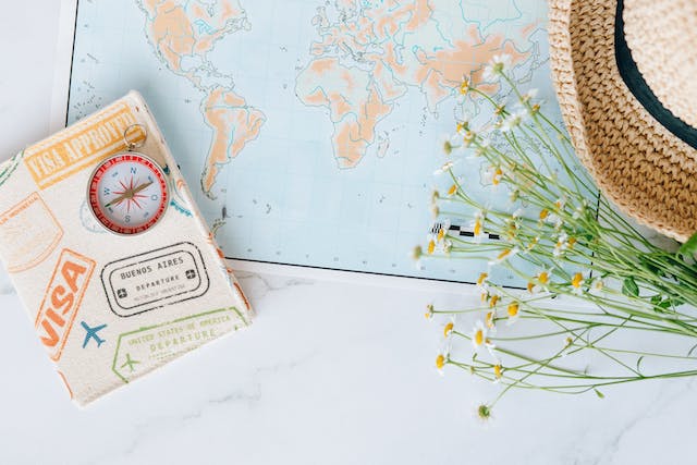 Ein Kompass, ein genehmigtes Visum und eine Blume auf einer Landkarte.
