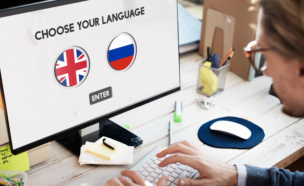 Eine Person benutzt einen Laptop, auf dem der Satz "Wählen Sie Ihre Sprache" steht.