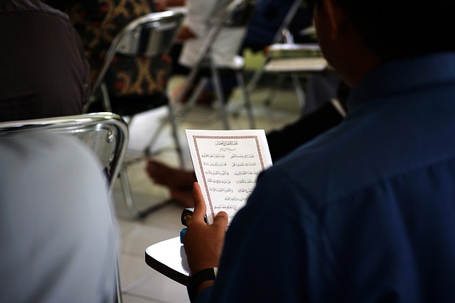 Eine Person liest einen arabischen Text auf einem Blatt Papier.