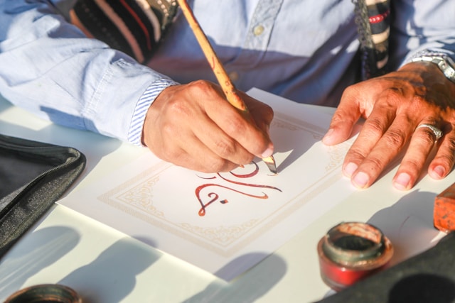Eine Person schreibt arabische Kalligrafie.