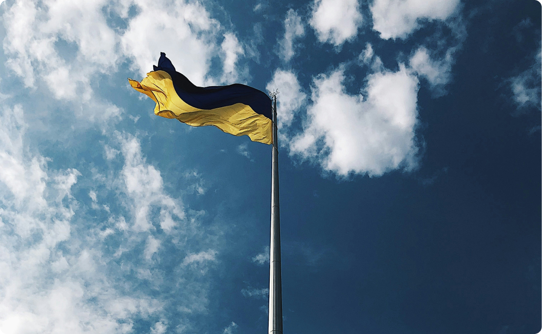 Una bandera ucraniana en un asta con el cielo de fondo, que representa ejemplos reales de traducciones de ucraniano.