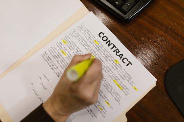 Una foto de una persona subrayando con tinta amarilla algunas partes de un contrato.
