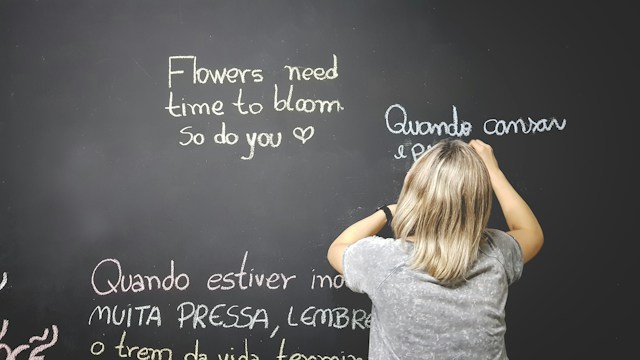 Un profesor utiliza tiza blanca para escribir inglés y portugués en una pizarra.
