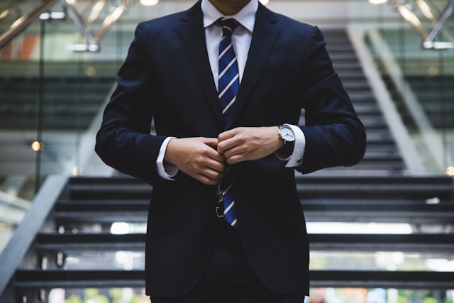 Una persona con un traje azul se para delante de una escalera.