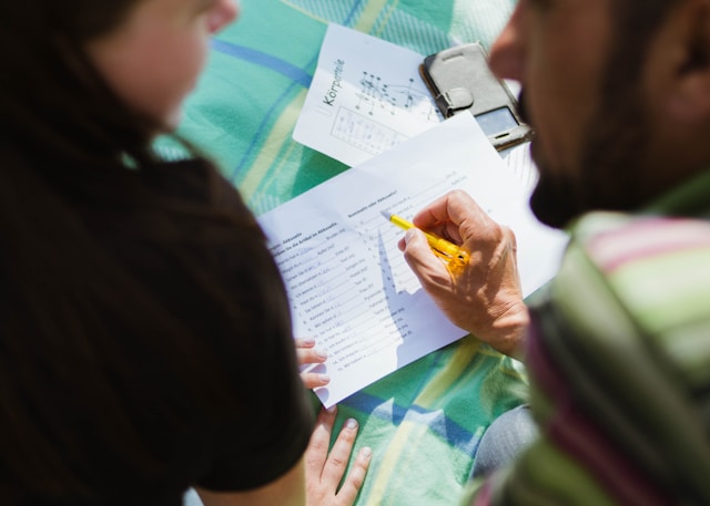 Dos personas rellenan un documento escrito en un idioma extranjero.
