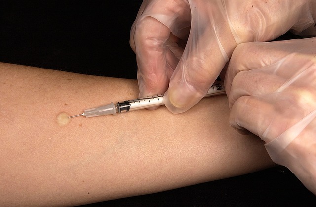 Una mano con guantes transparentes inyecta en el brazo de alguien.
