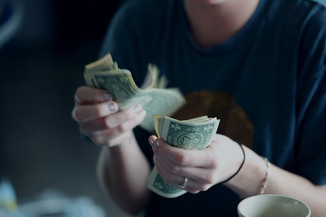 Una persona con camisa negra cuenta dinero.
