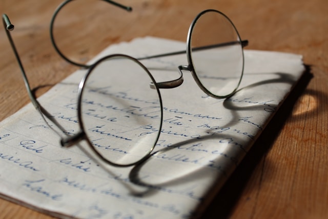 Un par de gafas sobre una escritura manuscrita.
