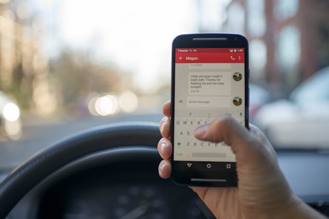 Una persona en un coche envía un mensaje en su teléfono Android.
