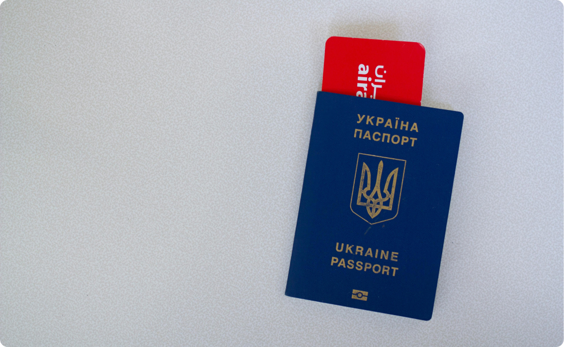 Passeport ukrainien bleu avec un billet d'avion rouge visible à l'intérieur sur fond gris.