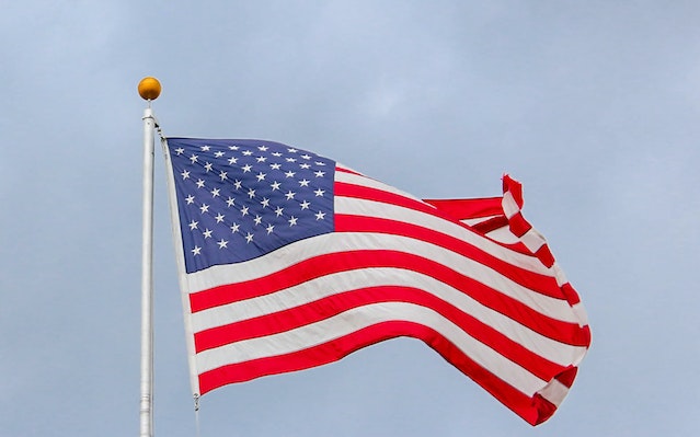 Drapeau américain flottant sur un mât métallique blanc.