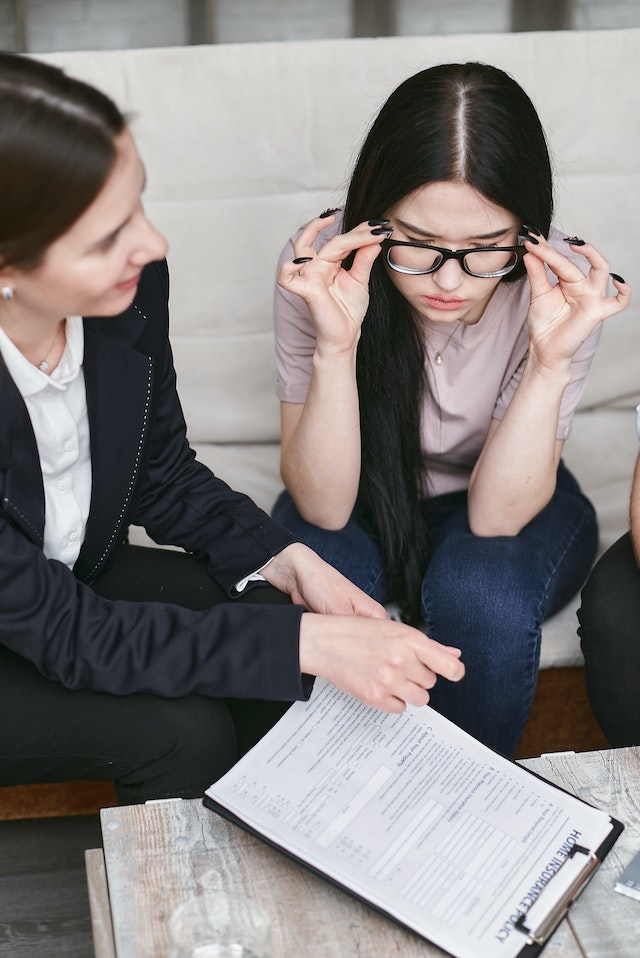 Professionnel aidant une femme à lunettes à signer un document officiel.