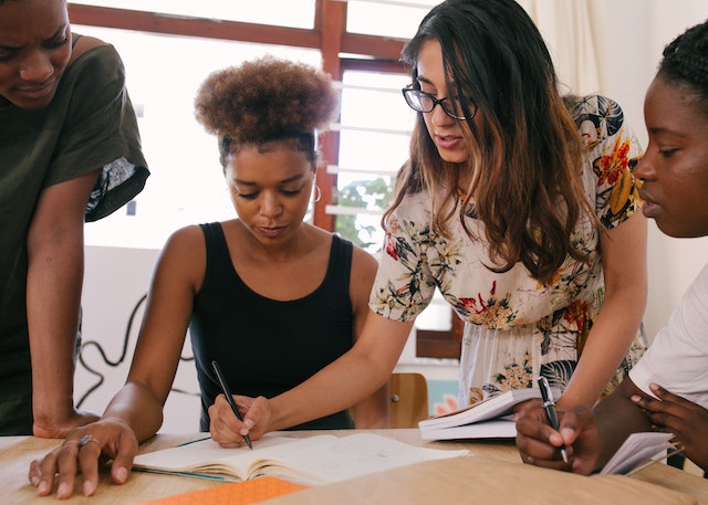 Une femme rédigeant des notes de traduction sur papier devant ses collègues.