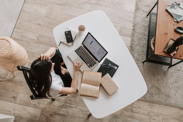 Jeune femme utilisant un ordinateur portable à une table dans un espace de travail moderne.