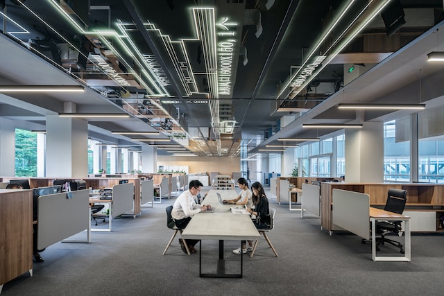 Photo de plusieurs personnes assises sur une table dans un bureau.
