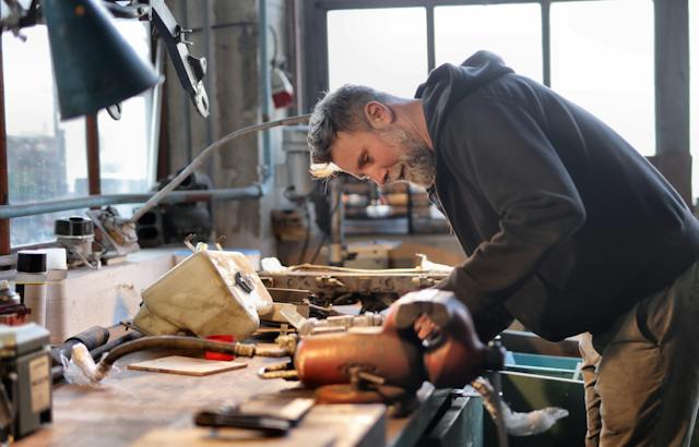 Photo d'une personne réparant des objets sur une table dans un garage.