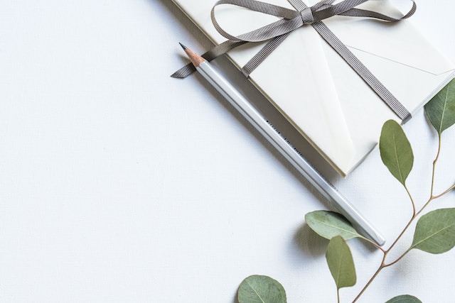 La photo d'un certificat emballé, d'un stylo et d'une branche de plante sur une table.