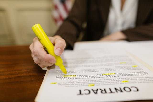 Image d'une personne surlignant à l'encre jaune certaines parties d'un contrat légal.