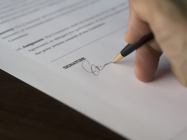 Une main appose une signature sur un document imprimé.
