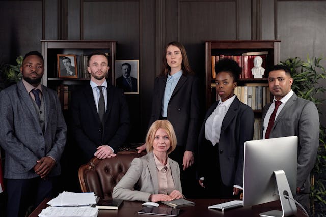 Un groupe de professionnels en costume derrière un bureau.
