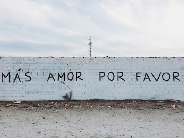 Un mur de béton gris avec des mots espagnols peints à l'encre noire.