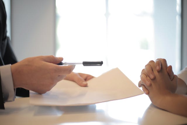 Une personne remet des documents à une autre.
