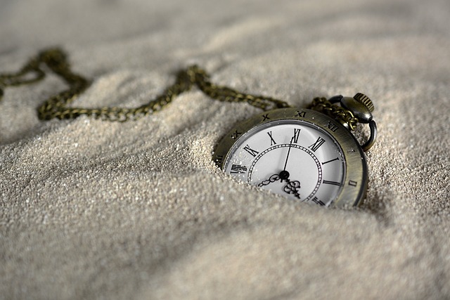 Un chronomètre est à moitié enterré dans le sable blanc.
