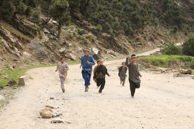 Plusieurs enfants jouent sur un chemin de sable.
