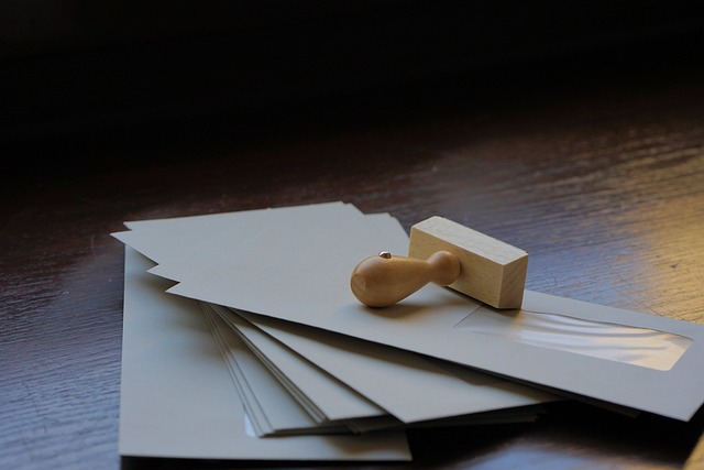 Un timbre en bois sur plusieurs enveloppes posées sur une table.
