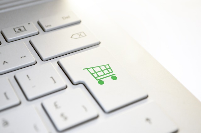 Le symbole d'un panier d'achat se trouve sur un bouton d'un clavier d'ordinateur blanc.
