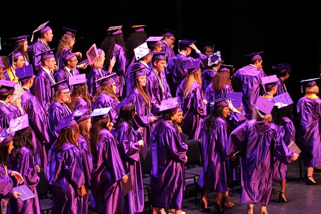 Un groupe de personnes vêtues de robes et de bonnets de fin d'études violets.
