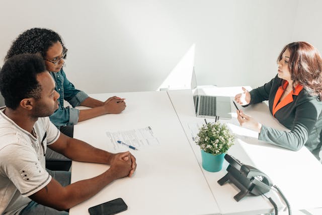 Un couple et un fonctionnaire s'entretiennent dans un bureau.